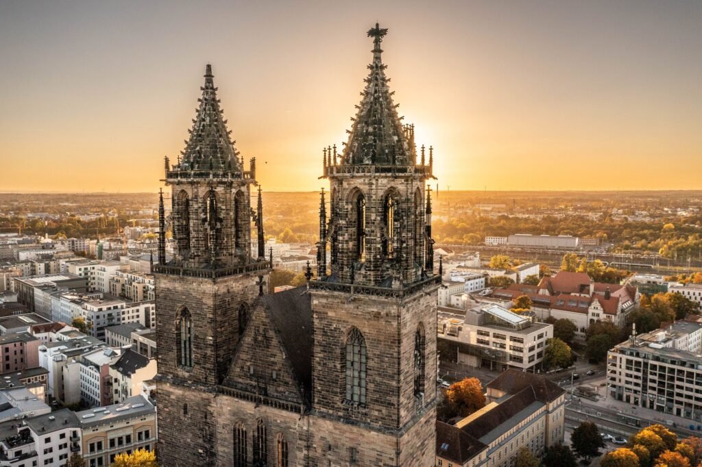 A scenic view of Magdeburg's historic skyline along the Elbe River at sunset.